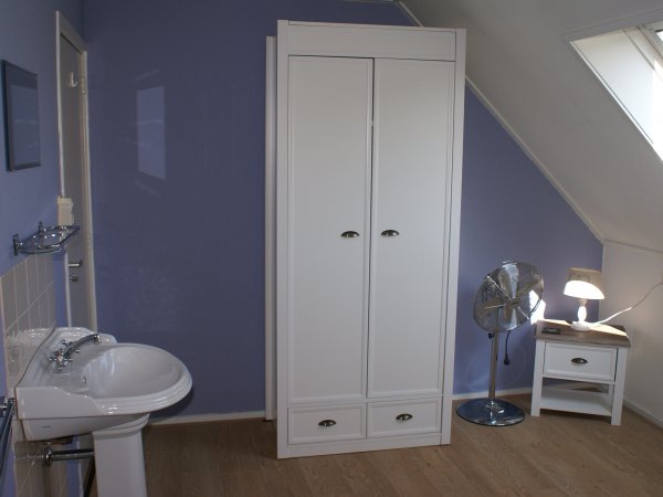 Een van de slaapkamers met wasbak en kledingkast