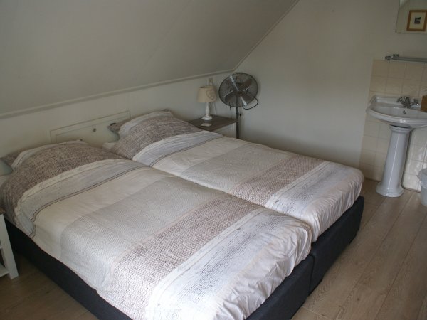 Een van de tweepersoonskamers boven met wastafel