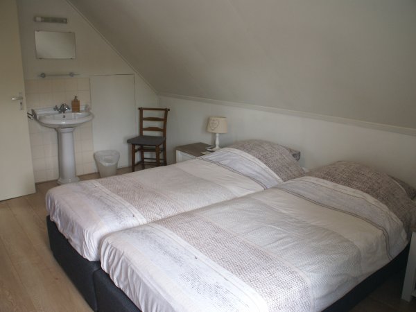 Een van de tweepersoonskamers boven met wastafel